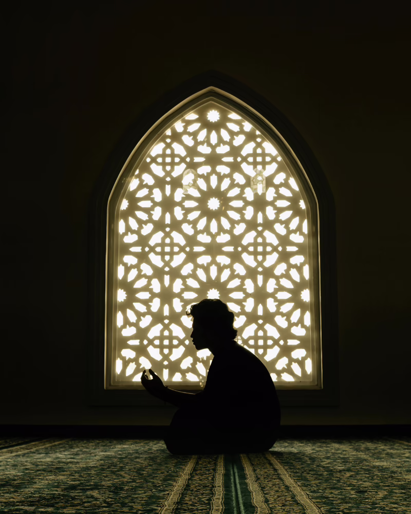 person meditating sat down with a patterned window behind